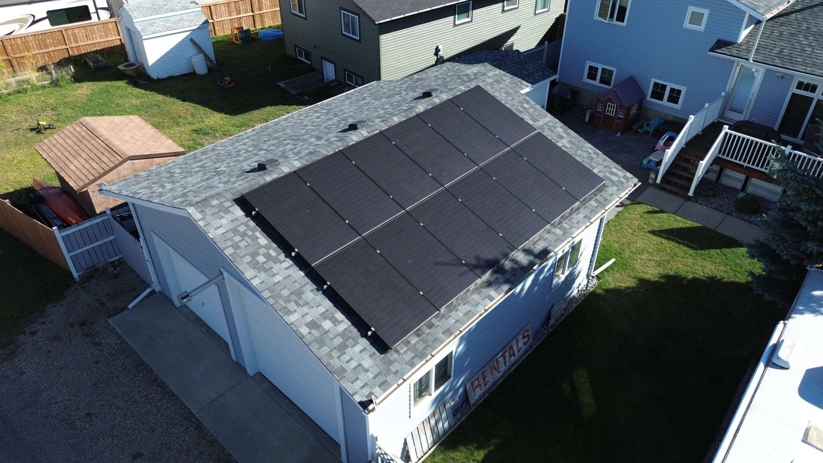 Aerial view of a home with solar panels on the garage roof.