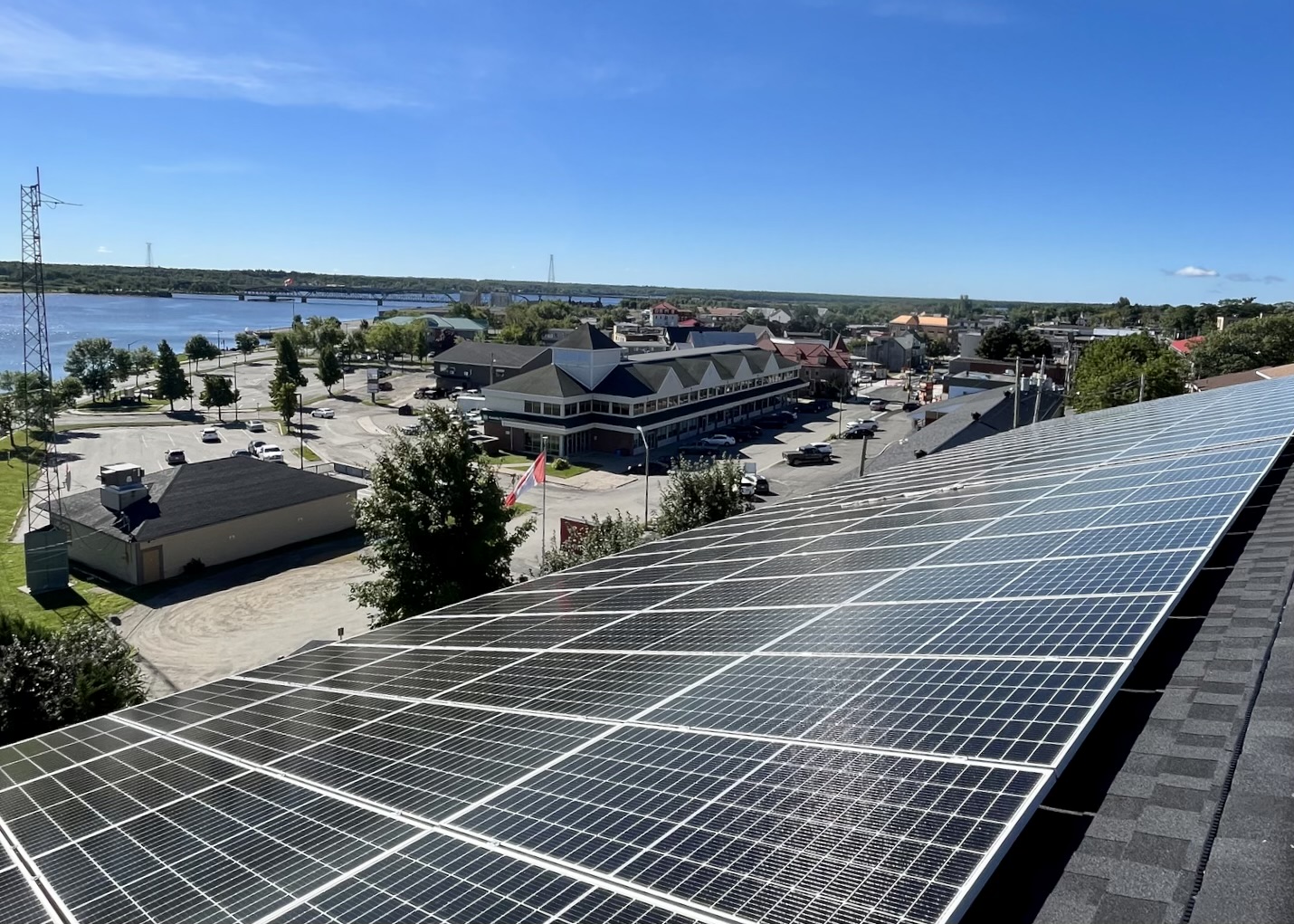 Rooftop view of solar panels on the roof of a Miramichi building, looking over the city and river.