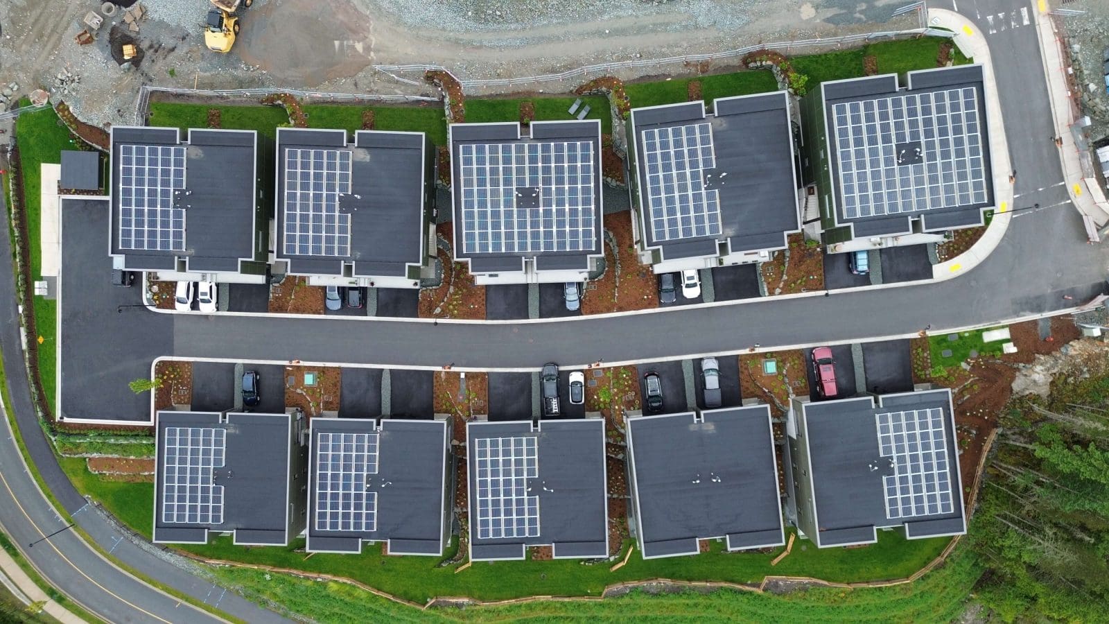 Aerial top-down view of a housing development with a series of townhouses with solar panels on the roofs.