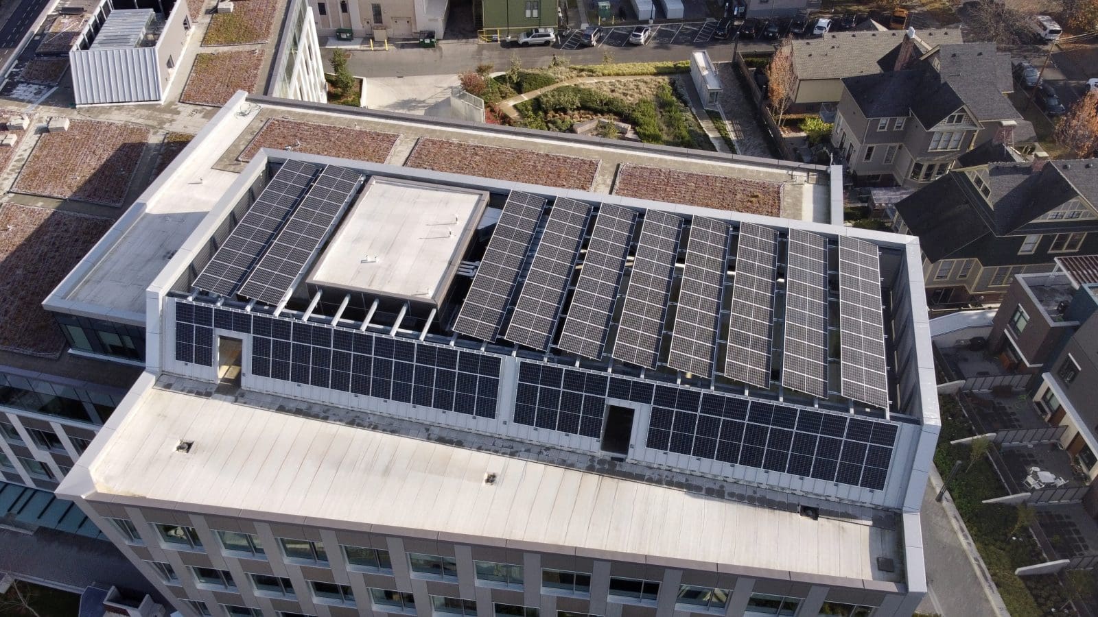 Aerial view of a large commercial building with multiple solar arrays on the roof.