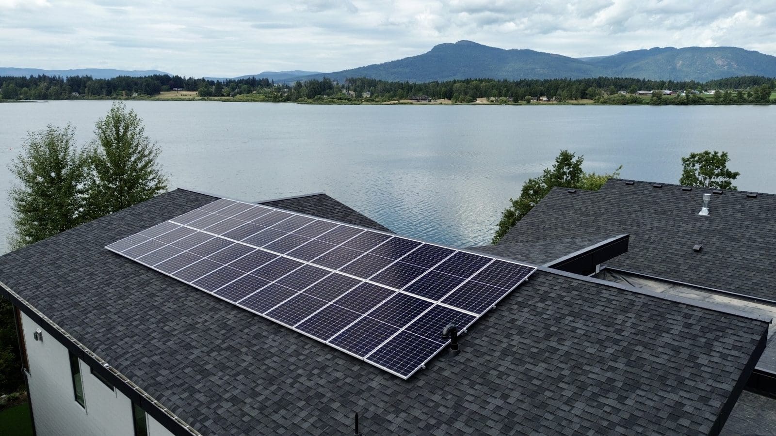 A lake front home with solar panels on the roof.