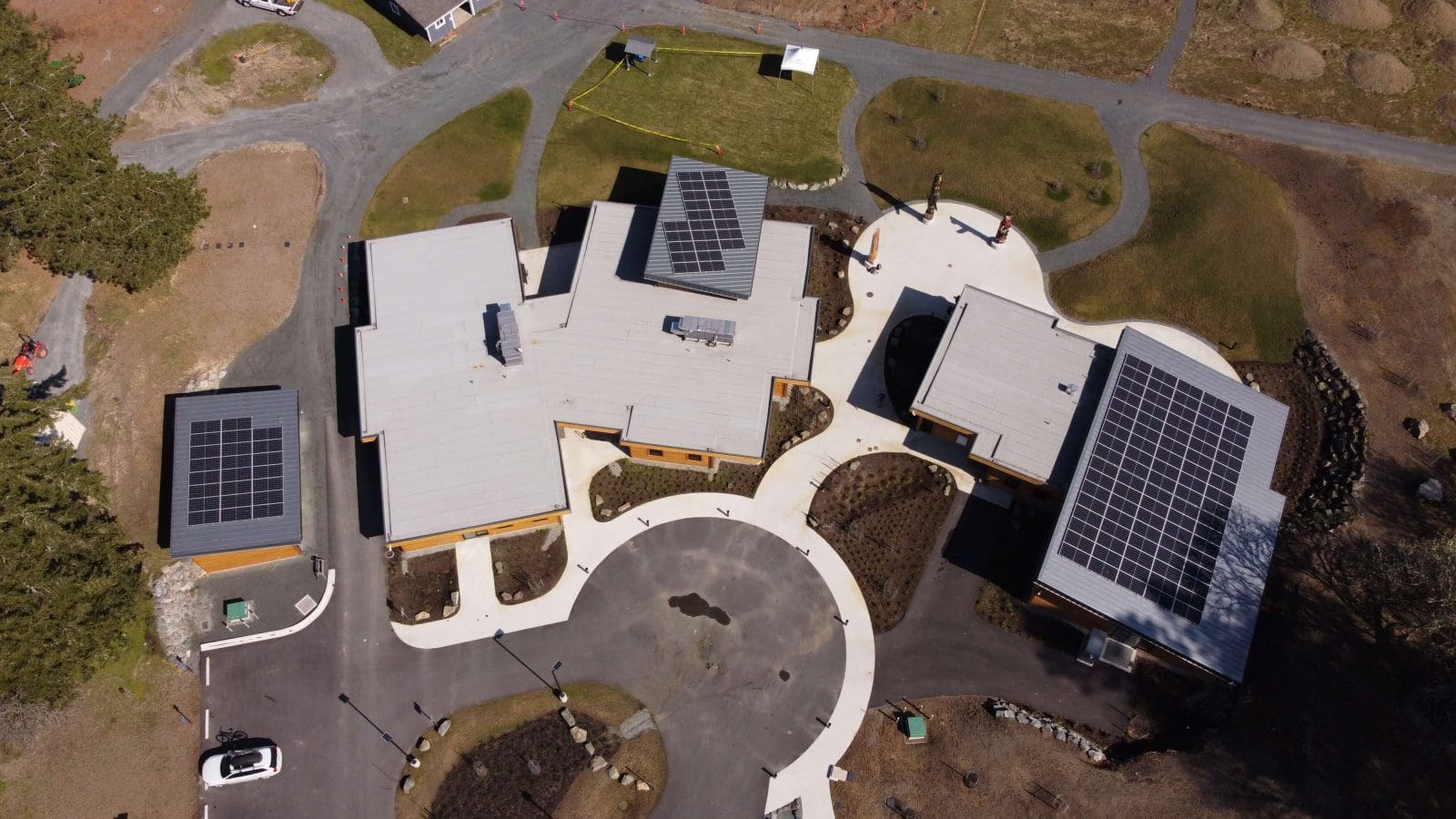 Overhead view looking down on a group of 3 community buildings, part of a local non-profit. There are 3 separate solar arrays on display, 1 on each building.
