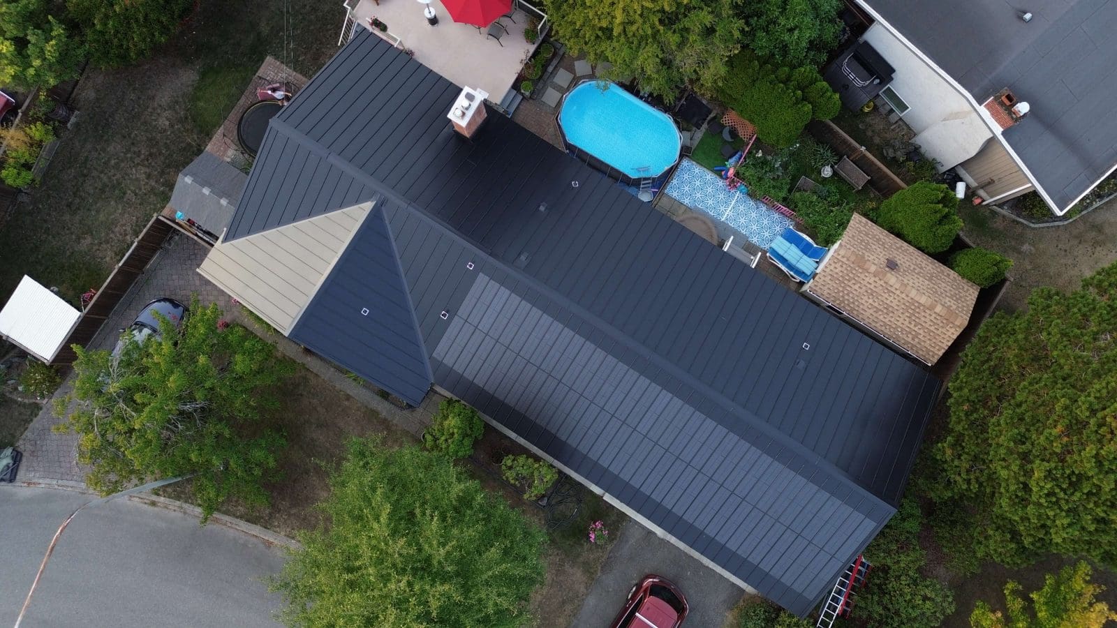 Overhead view, looking down on a home with Building Integrated Photovoltaic solar panels. It has a black metal roof and the solar panels are seemlessly integrated into the roof structure.