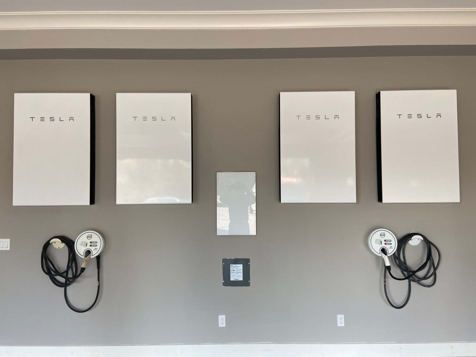 4 Tesla Powerwalls installed on a garage wall, with 2 EV chargers below.